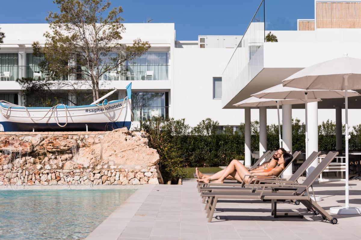 Dos mujeres sentadas en tumbonas junto a una piscina en Petit Sagitario Adults only, en Ciutadella