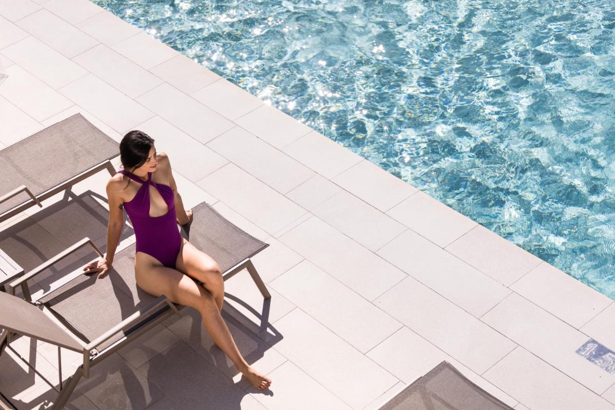 una mujer sentada en una silla junto a una piscina en Petit Sagitario Adults only, en Ciutadella