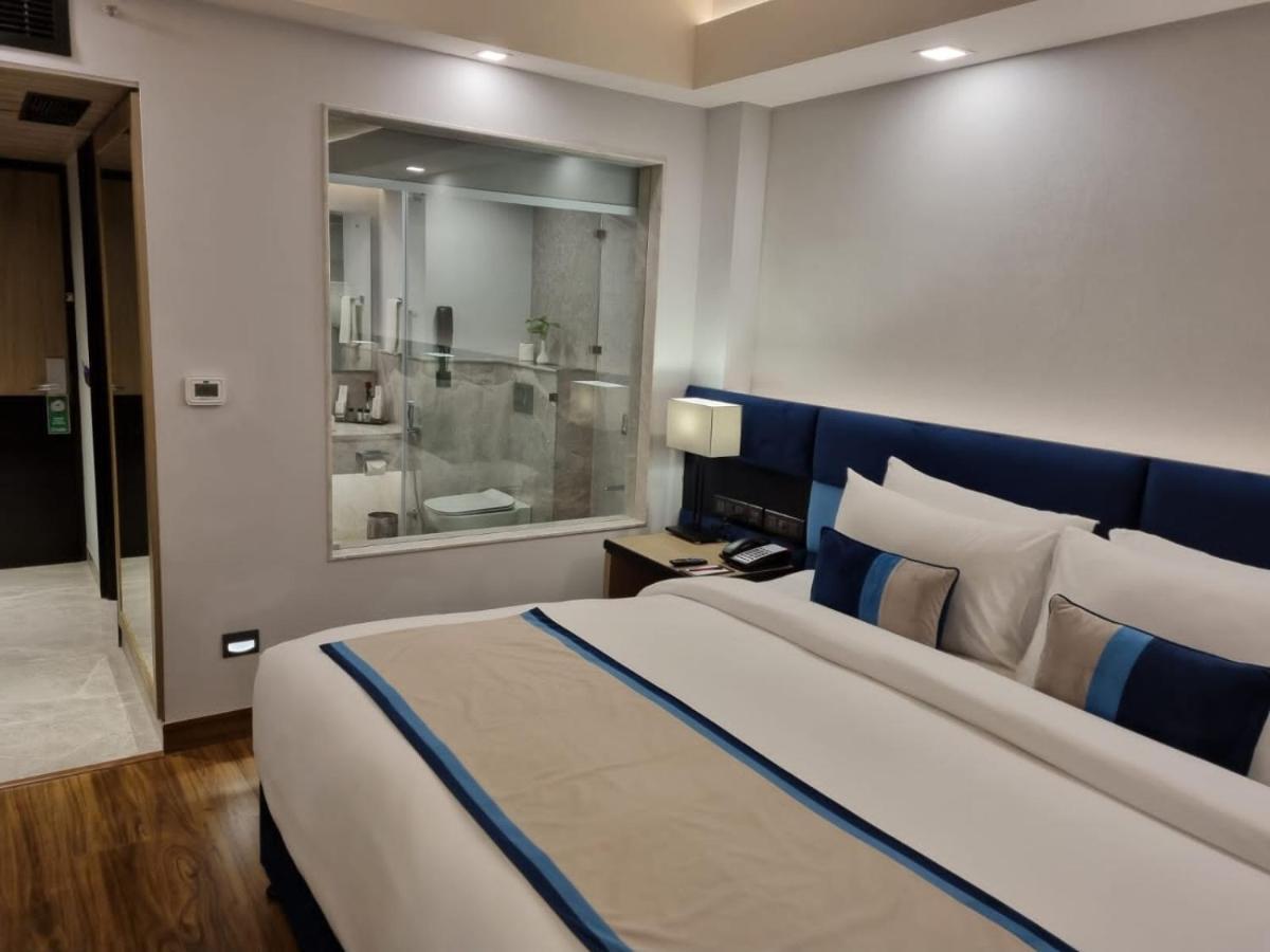 a bedroom with a large bed and a bathroom at The Piccadily in Lucknow