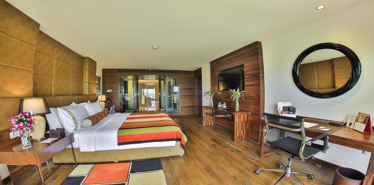 a bedroom with a bed and a desk and a mirror at The Lalit Chandigarh in Chandīgarh