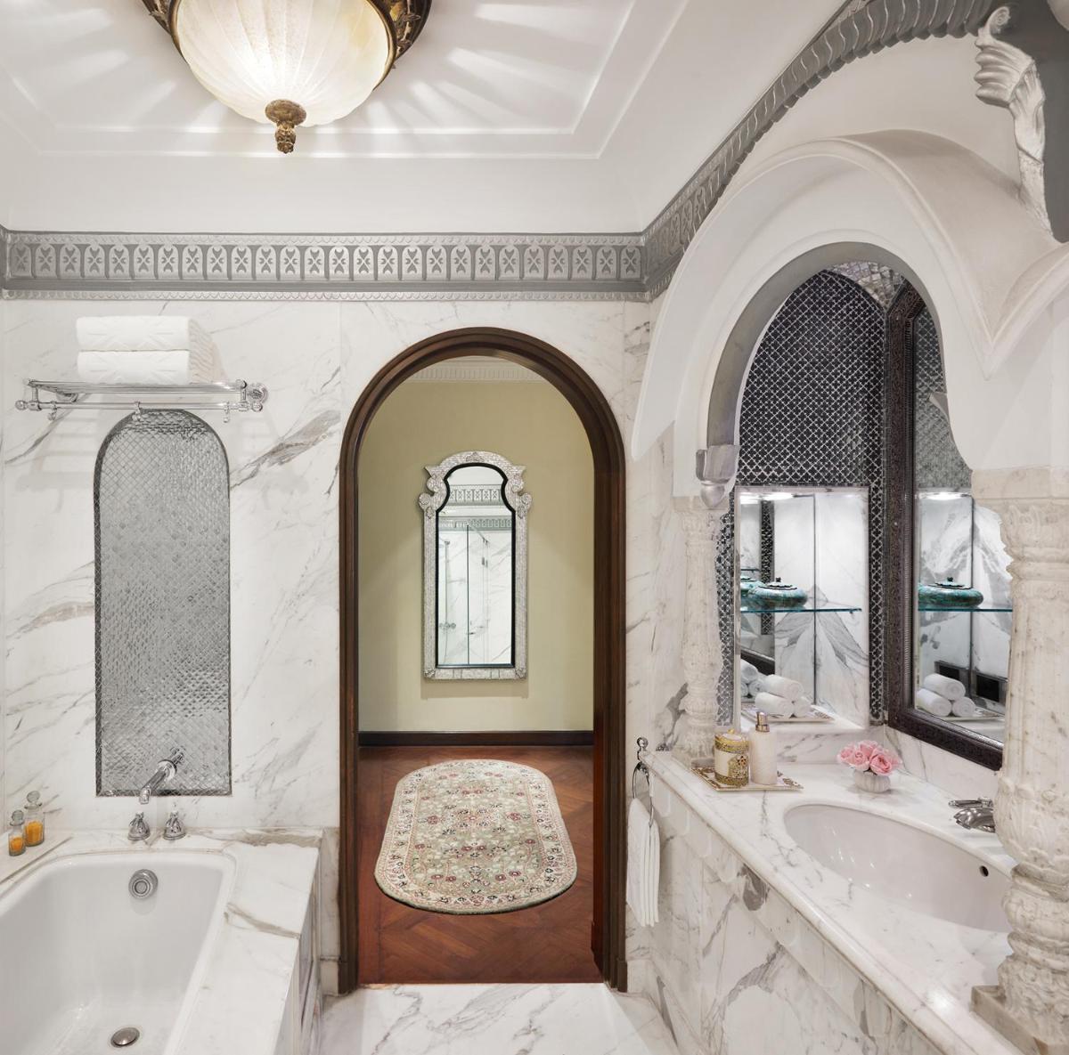 a bathroom with two sinks and a tub and a mirror at Rambagh Palace in Jaipur a bathroom with two sinks and a tub and a mirror at Rambagh Palace in Jaipur