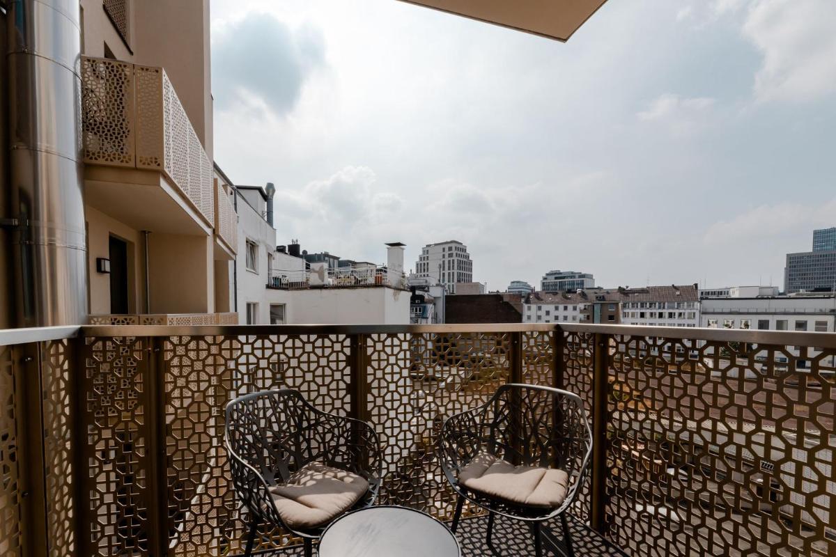 einen Balkon mit 2 Stühlen und Stadtblick in der Unterkunft Fourty Three Luxury Serviced Apartments in Düsseldorf