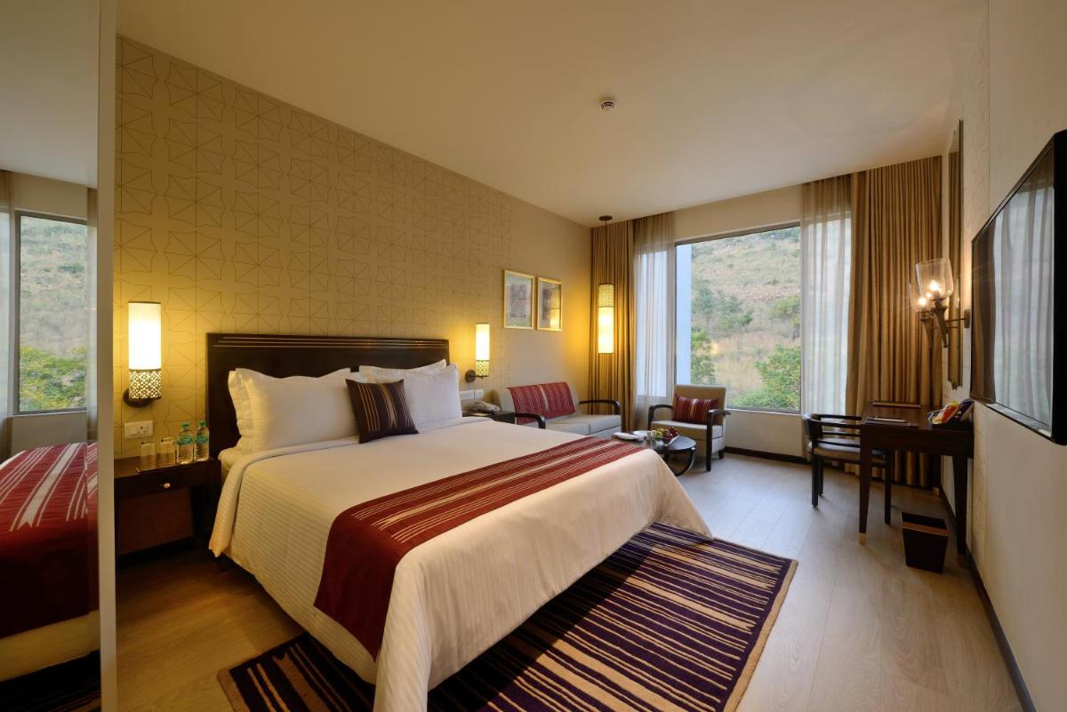 a hotel room with a large bed and a desk at Marasa Sarovar Premiere in Tirupati