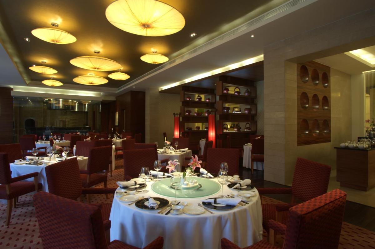 a dining room with tables and chairs and lights at Taj Coromandel in Chennai