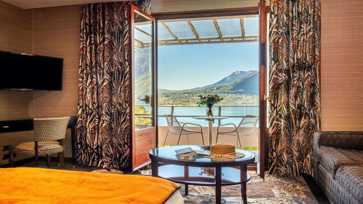 Cette chambre dispose d'un lit et d'un balcon avec une table. dans l'établissement Les Trésoms Lake and Spa Resort, à Annecy