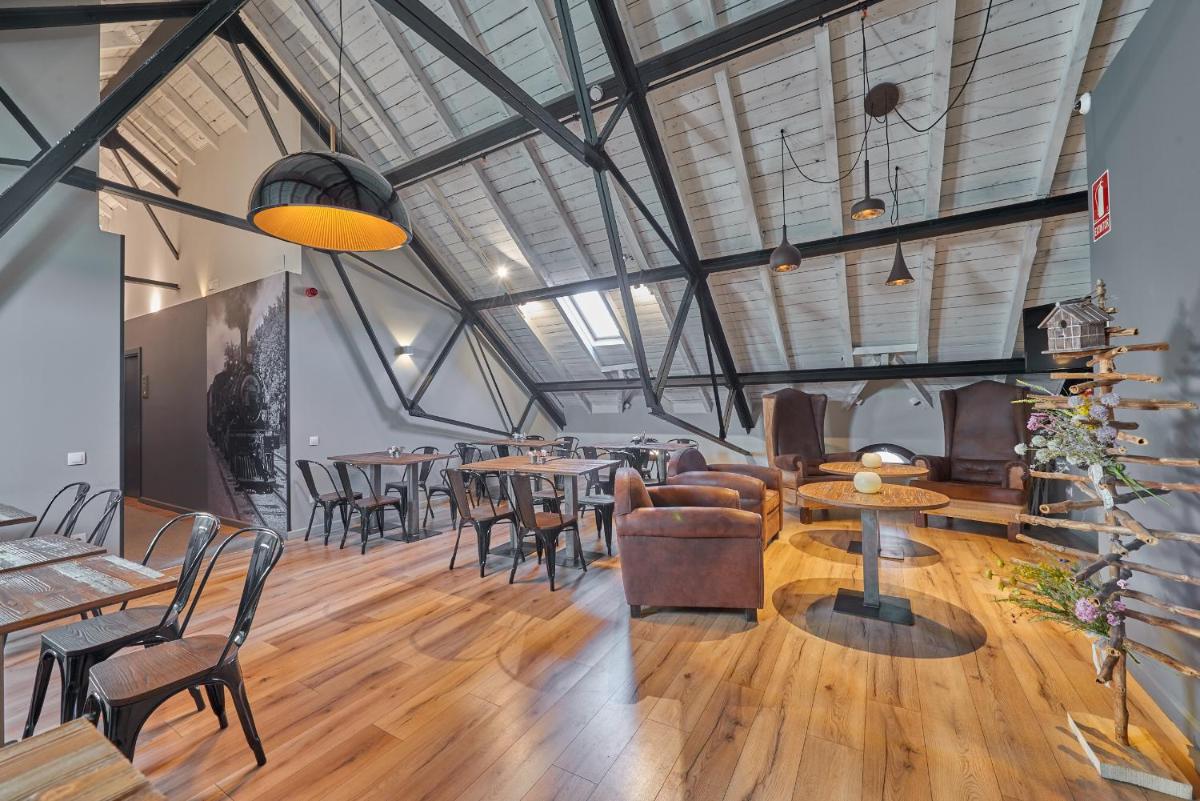 Un comedor con mesas y sillas y ventanas. en Hotel Parada Puigcerda, en Puigcerdà