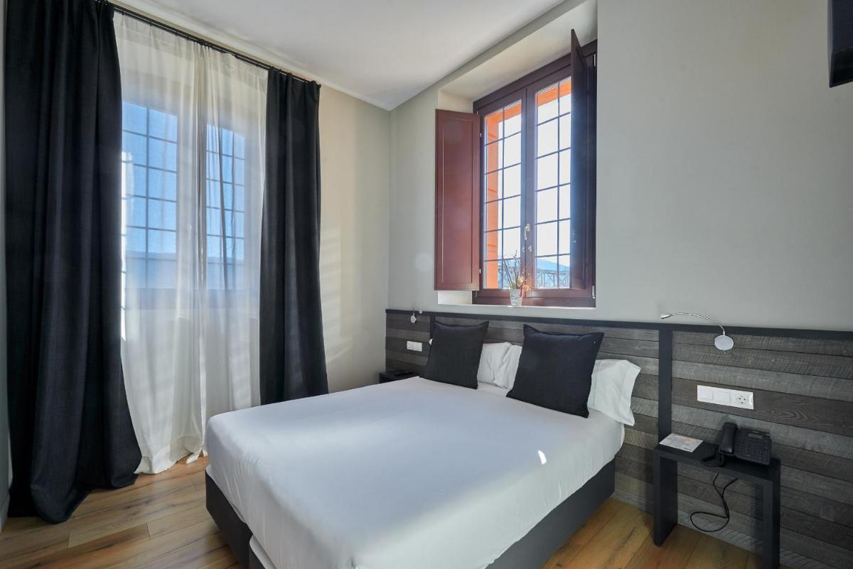 Un dormitorio con una gran cama blanca y una ventana. en Hotel Parada Puigcerda, en Puigcerdà