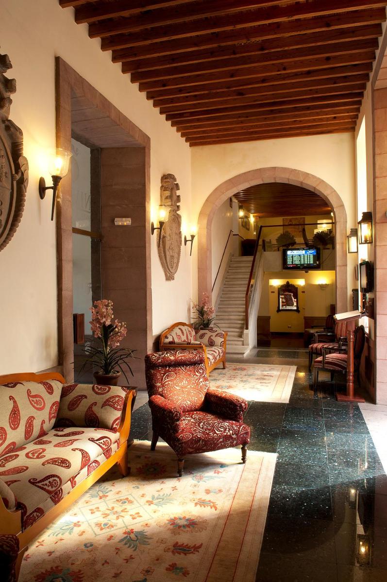 Una sala de estar con un sofá y sillas y una escalera. en Laguna Nivaria Hotel & Spa, en La Laguna