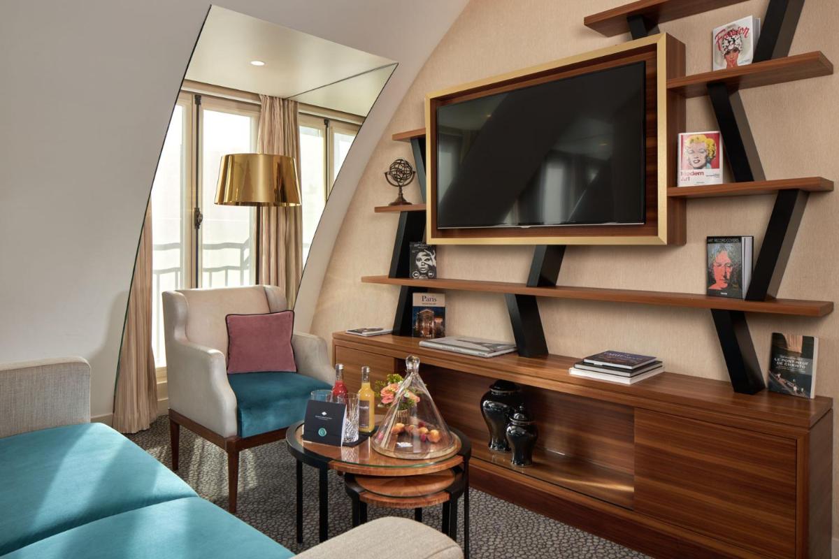 un salon avec une télévision sur un mur dans l'établissement Maison Albar - Le Pont-Neuf, à Paris