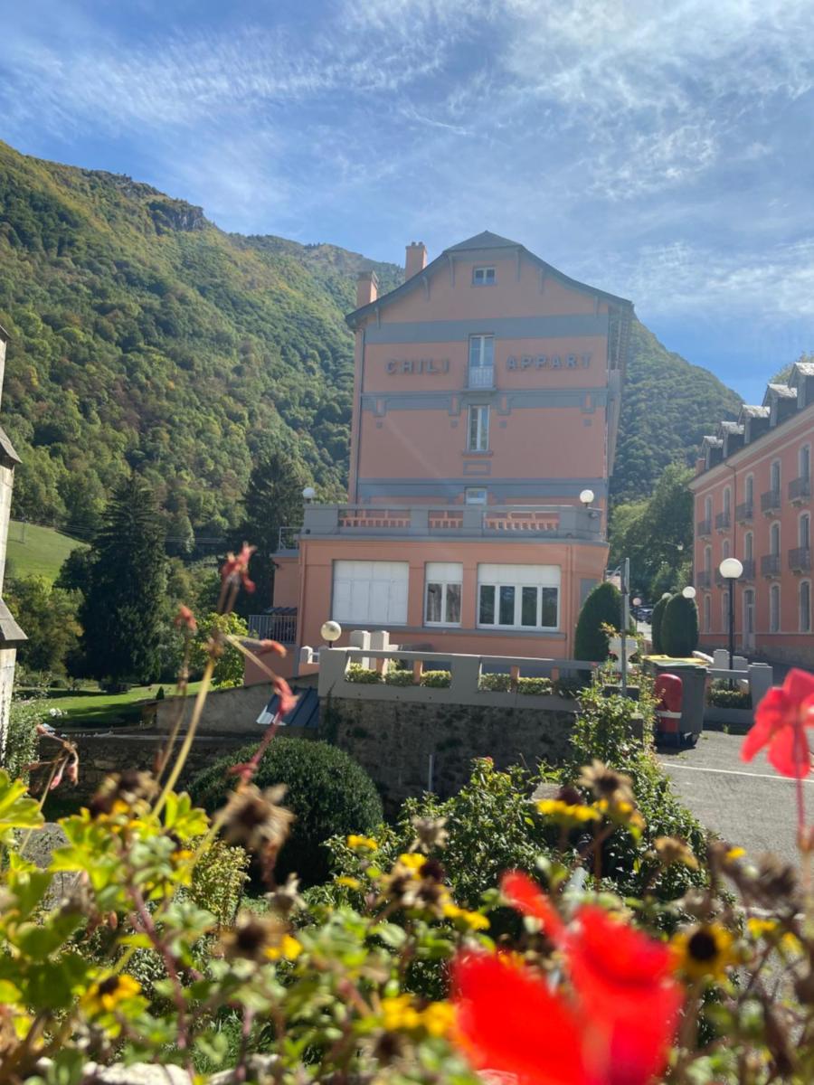 un grand bâtiment rose en face d'une montagne dans l'établissement Appart Le Chili- Quartier thermal- Parc remarquable - Linge fourni, à Luz-Saint-Sauveur