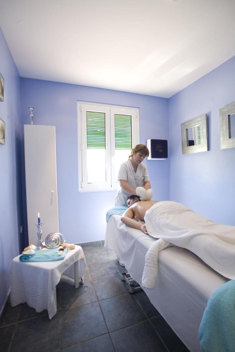 una mujer sentada en una cama en una habitación de hospital en Hotel Balneario El Raposo, en Puebla de Sancho Pérez