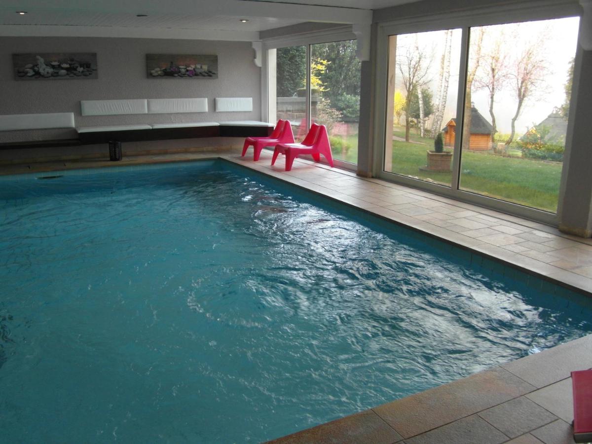 une piscine avec des chaises rouges dans une maison dans l'établissement Spa Hôtel Restaurant Au Lion d'Or, à La Petite-Pierre