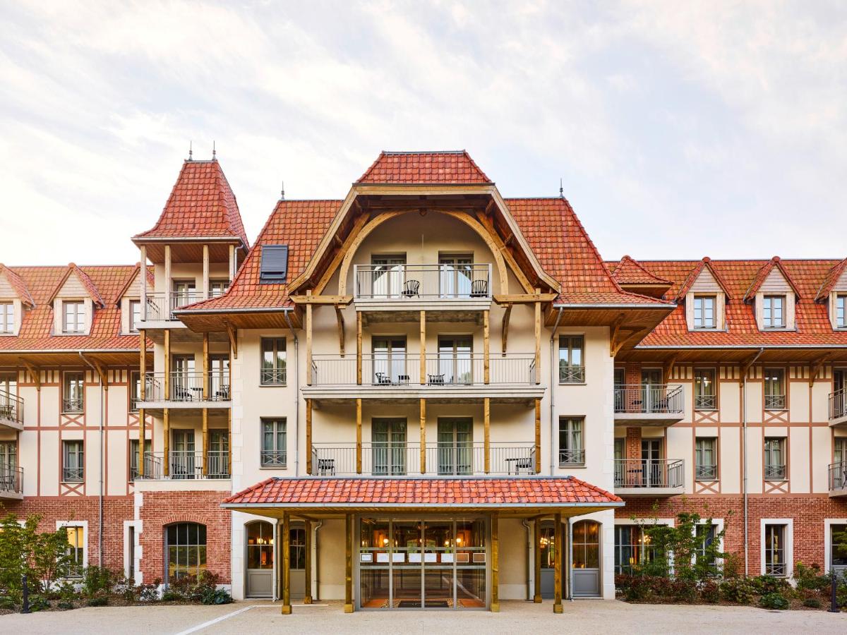 un grand bâtiment avec des toits de tuiles rouges dans l'établissement TRIBE Hôtel Le Touquet, à Le Touquet-Paris-Plage
