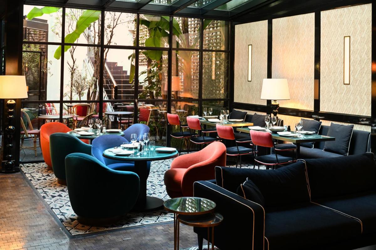 un restaurant avec des tables, des chaises et des fenêtres dans l'établissement Le Roch Hotel & Spa, à Paris