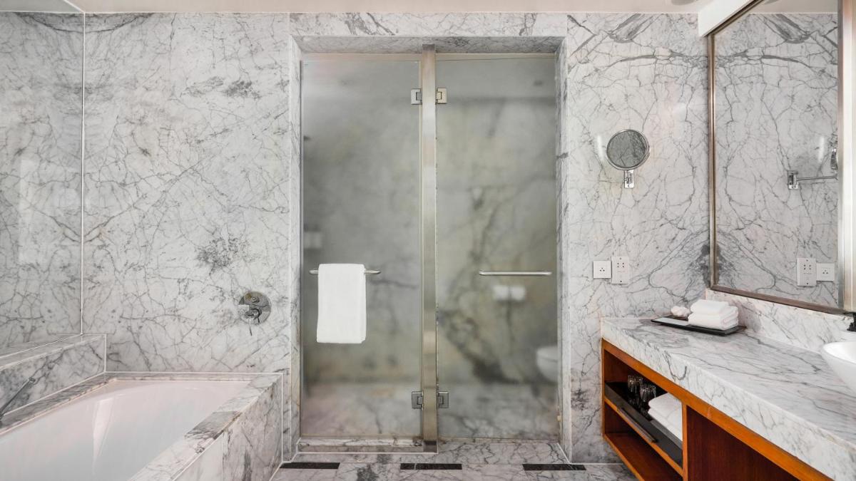 a bathroom with a shower and a tub and a sink at InterContinental Marine Drive Mumbai by IHG in Mumbai