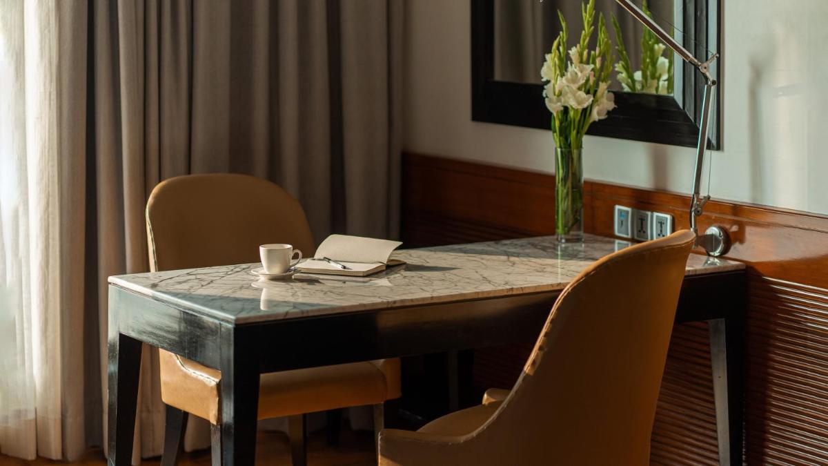 a table with chairs and a laptop and a vase of flowers at InterContinental Marine Drive Mumbai by IHG in Mumbai