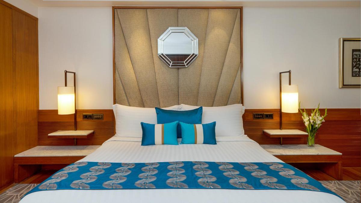 a bedroom with a large bed with blue pillows at InterContinental Marine Drive Mumbai by IHG in Mumbai