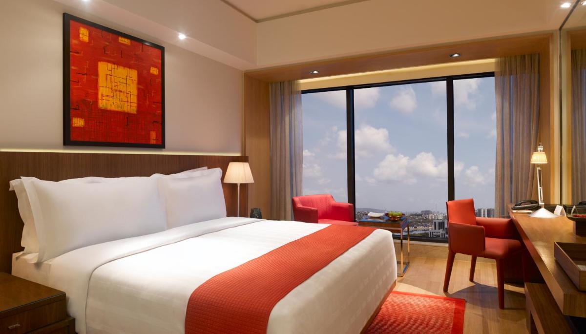a hotel room with a bed and a desk and a window at Trident Bandra Kurla in Mumbai a hotel room with a bed and a desk and a window at Trident Bandra Kurla in Mumbai