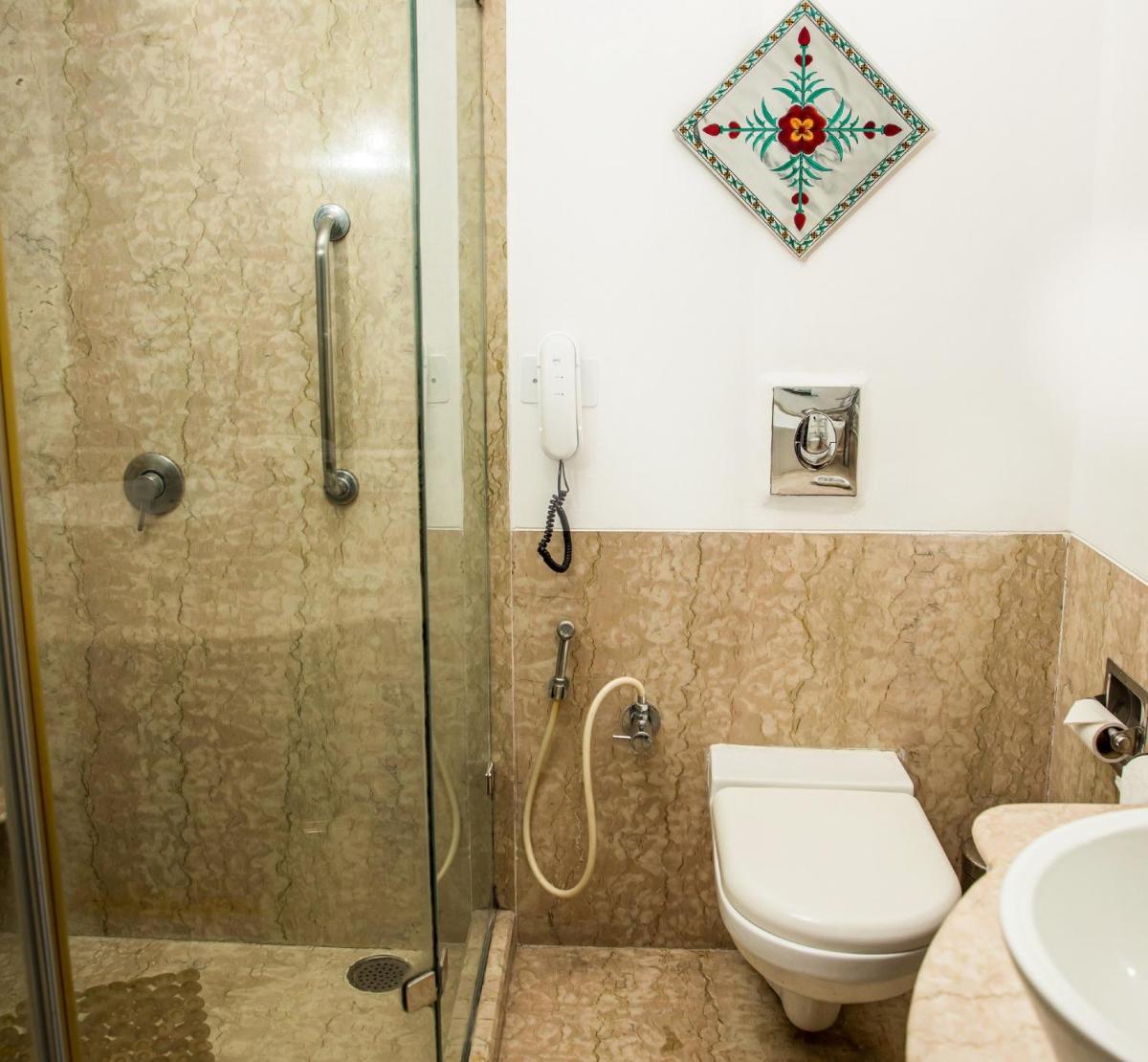 a bathroom with a shower and a toilet and a sink at The Lalit Laxmi Vilas Palace in Udaipur