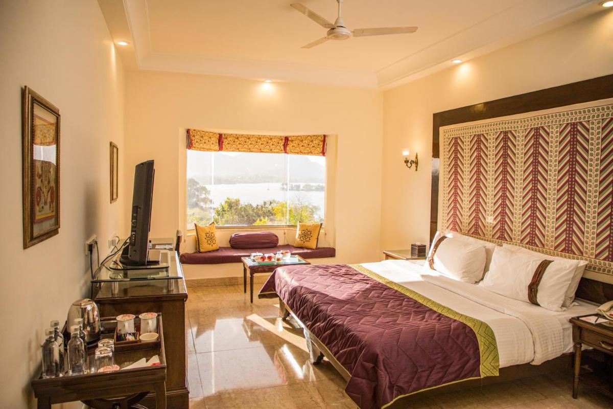 a bedroom with a bed and a living room at The Lalit Laxmi Vilas Palace in Udaipur