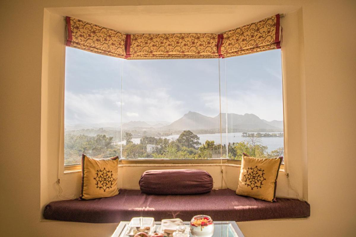a window seat in front of a large window with a view at The Lalit Laxmi Vilas Palace in Udaipur