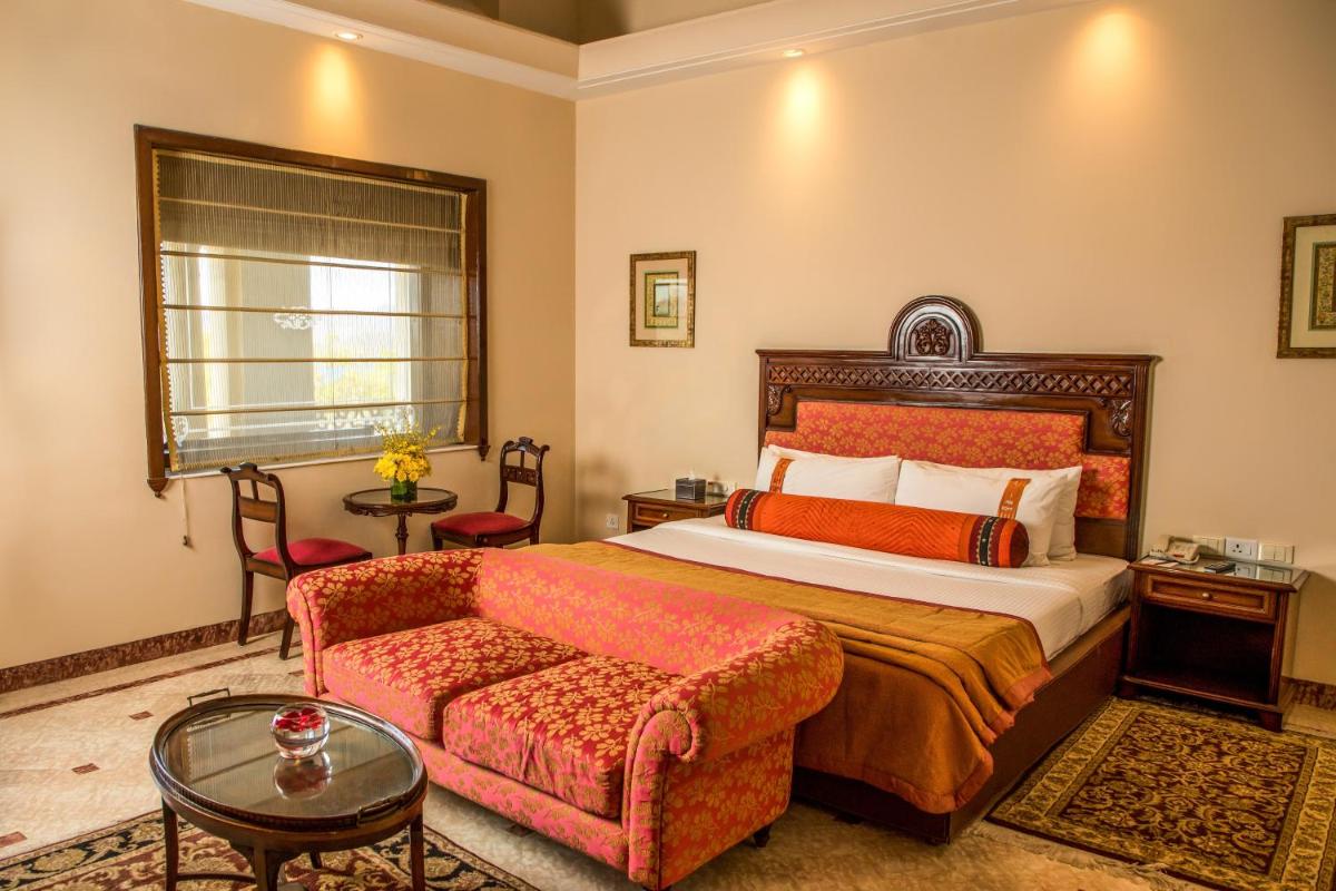 a hotel room with a bed and a couch at The Lalit Laxmi Vilas Palace in Udaipur