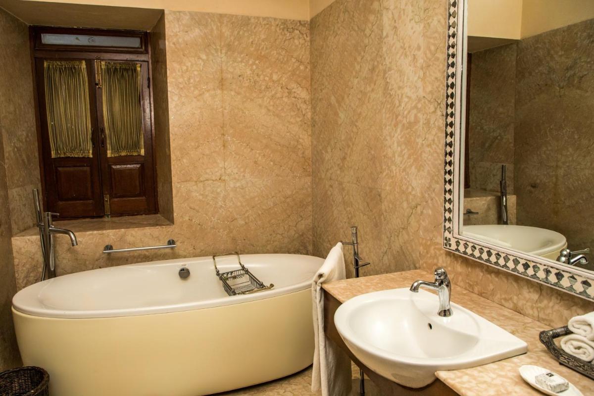 a bathroom with a tub and a sink and a mirror at The Lalit Laxmi Vilas Palace in Udaipur
