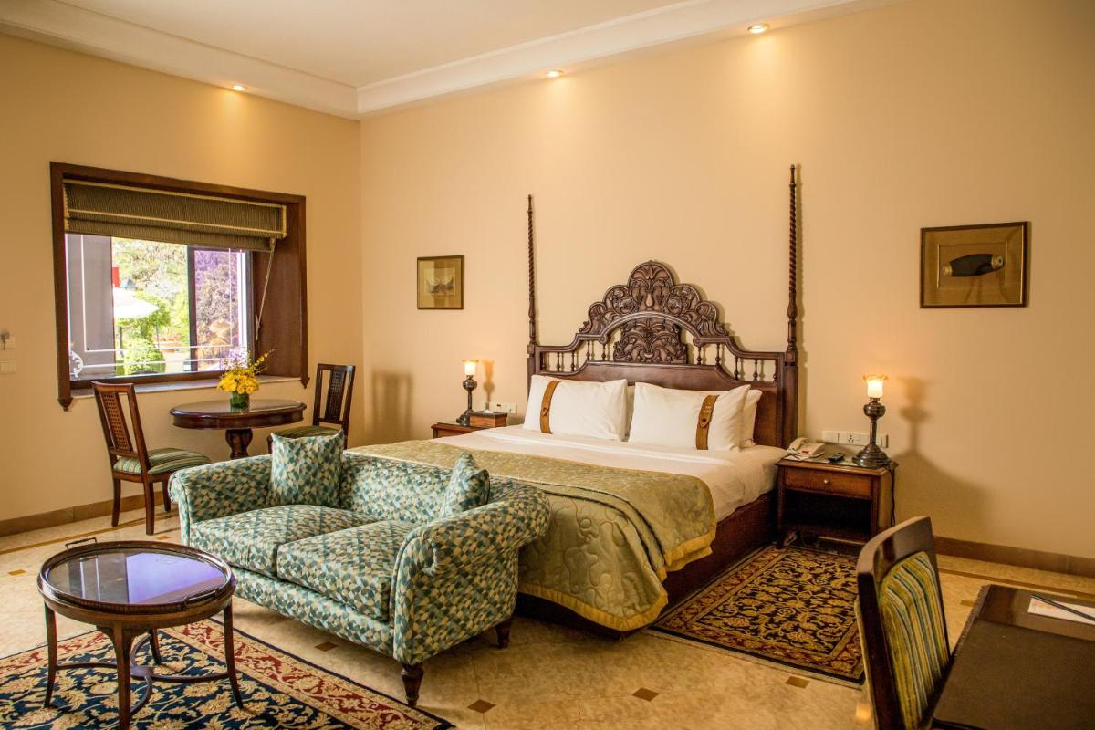 a bedroom with a bed and a chair at The Lalit Laxmi Vilas Palace in Udaipur +155 photos