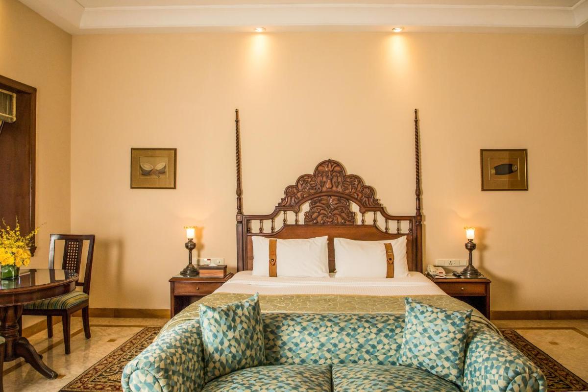 a bedroom with a bed and a couch in front of it at The Lalit Laxmi Vilas Palace in Udaipur