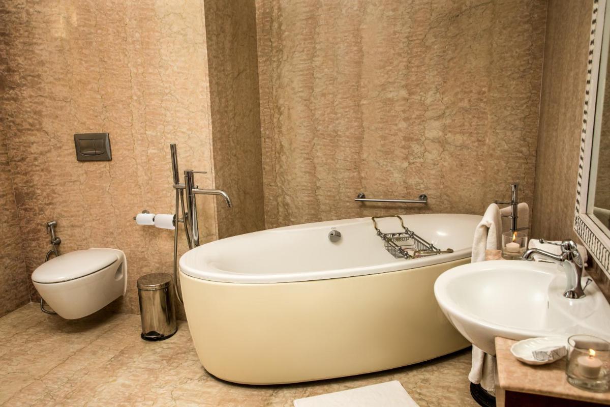 a bathroom with a tub and a toilet and a sink at The Lalit Laxmi Vilas Palace in Udaipur