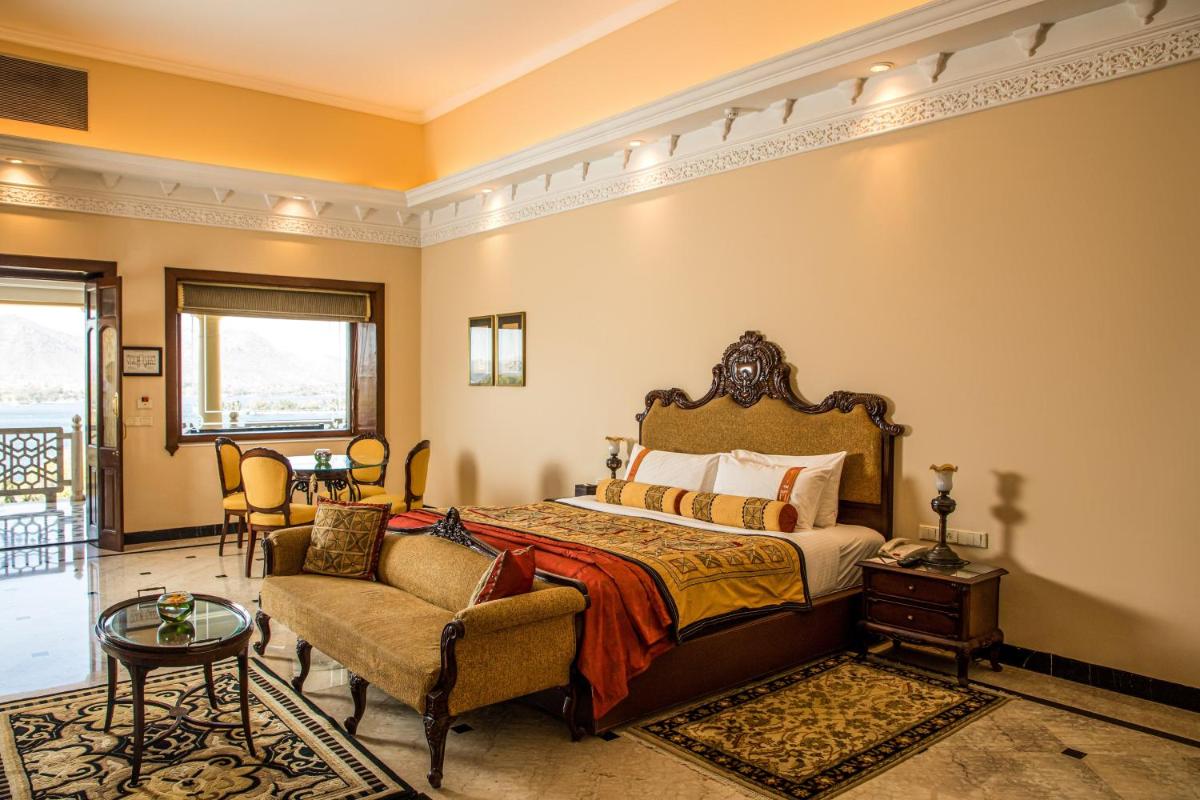 a bedroom with a bed and a couch and a chair at The Lalit Laxmi Vilas Palace in Udaipur