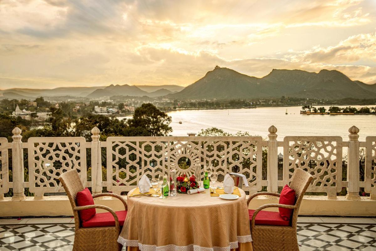 a table on a balcony with a view of the water at The Lalit Laxmi Vilas Palace in Udaipur