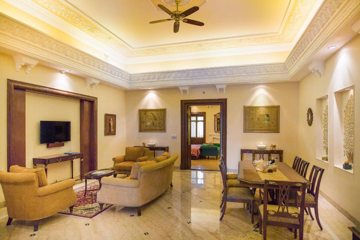 a living room with a ceiling fan and a dining room at The Lalit Laxmi Vilas Palace in Udaipur