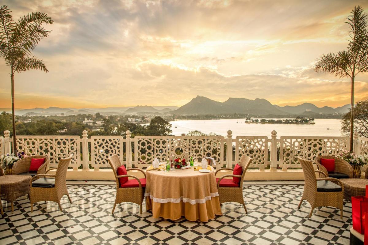 a table on a balcony with a view of the water at The Lalit Laxmi Vilas Palace in Udaipur