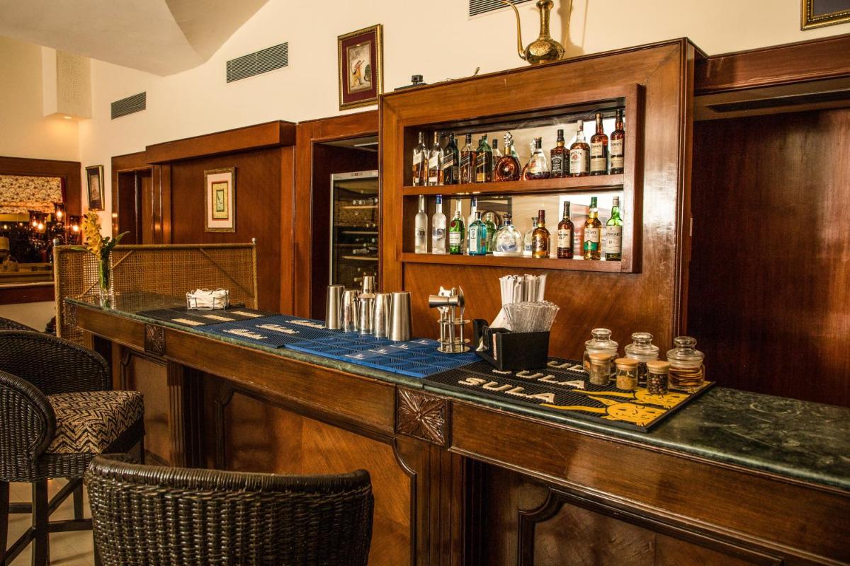 a bar in a restaurant with a counter with drinks at The Lalit Laxmi Vilas Palace in Udaipur