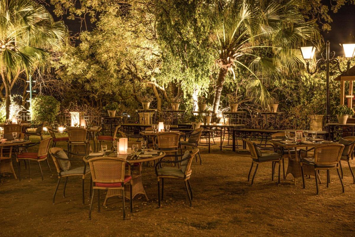 a restaurant with tables and chairs at night at The Lalit Laxmi Vilas Palace in Udaipur