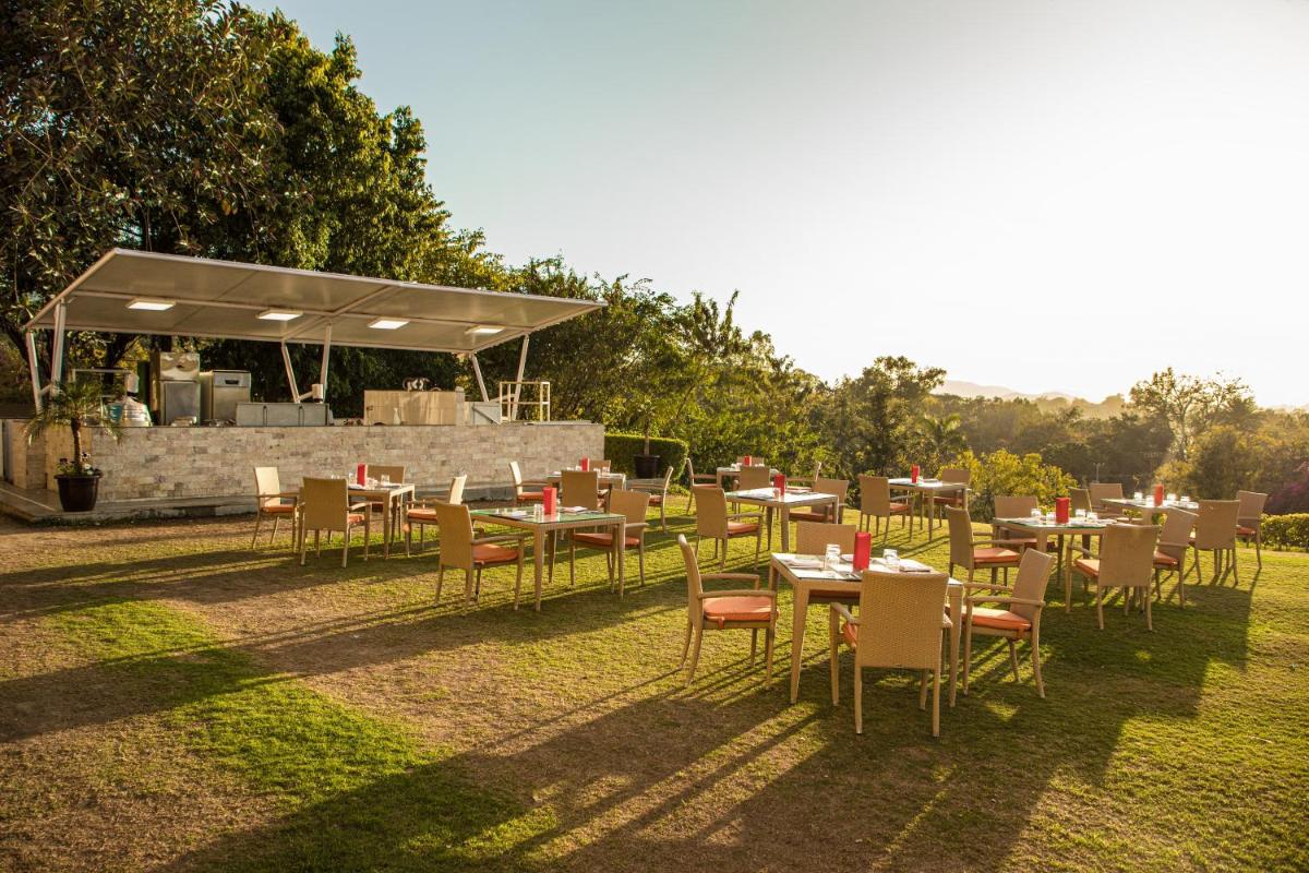 a group of tables and chairs in the grass at The Lalit Laxmi Vilas Palace in Udaipur