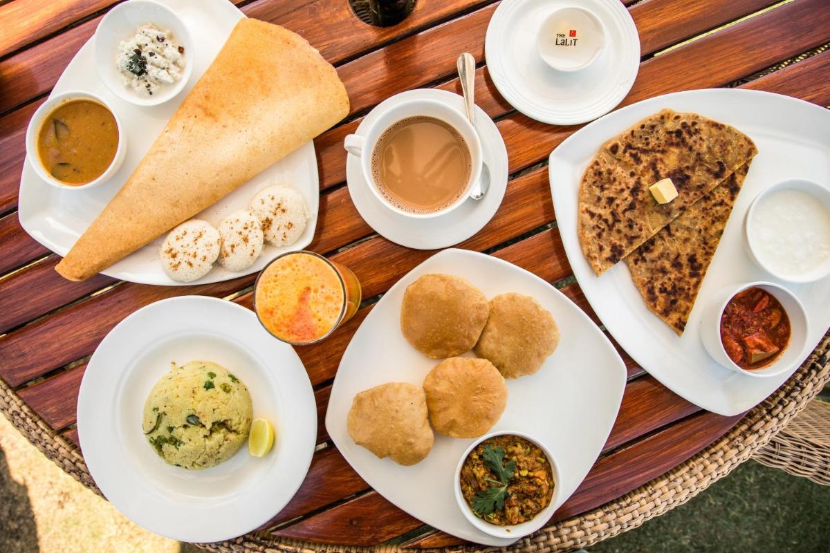 a table with plates of food and cups of coffee at The Lalit Laxmi Vilas Palace in Udaipur