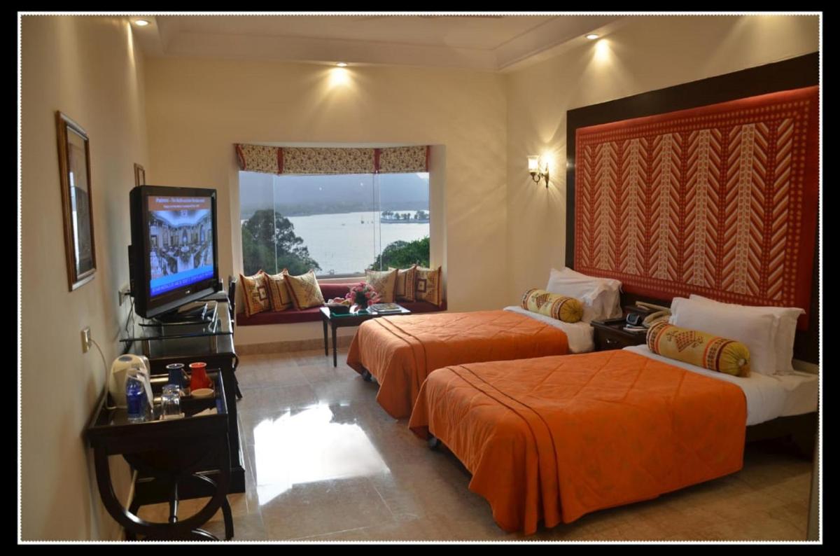 a hotel room with two beds and a flat screen tv at The Lalit Laxmi Vilas Palace in Udaipur