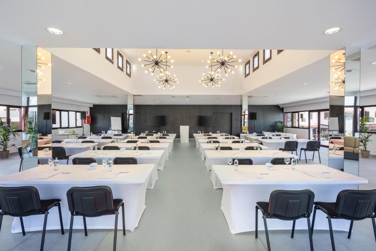 Un gran salón de banquetes con mesas y sillas blancas. en Occidental Roca Negra - Adults Only, en Agaete