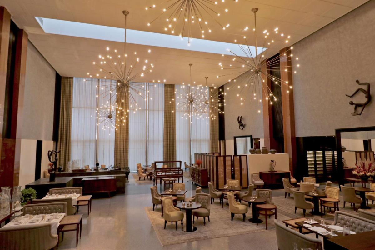 a lobby with tables and chairs and lights at Grand Hyatt Gurgaon in Gurgaon