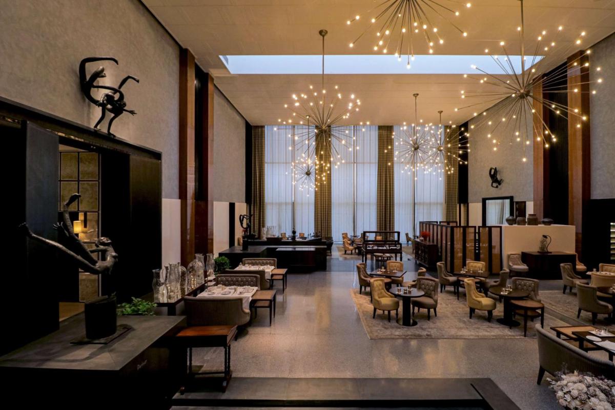 a lobby with chairs and tables and chandeliers at Grand Hyatt Gurgaon in Gurgaon