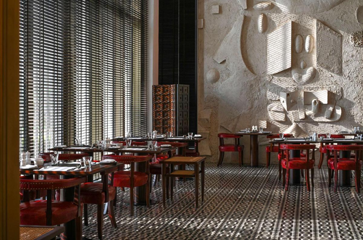 a restaurant with tables and red chairs in a room at Grand Hyatt Gurgaon in Gurgaon