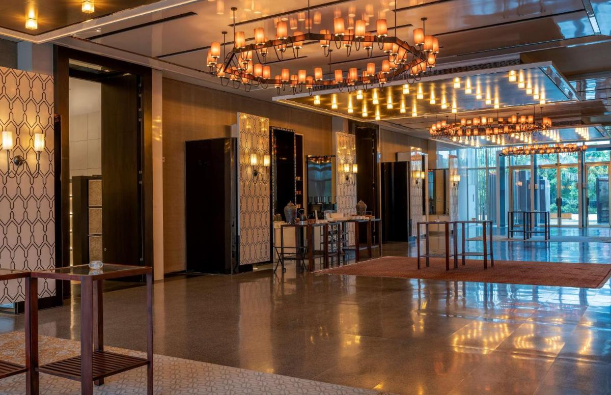 a lobby with a chandelier and tables and chairs at Grand Hyatt Gurgaon in Gurgaon