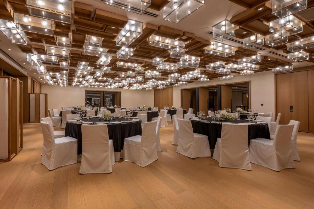 a banquet hall with tables and white chairs and chandeliers at Grand Hyatt Gurgaon in Gurgaon