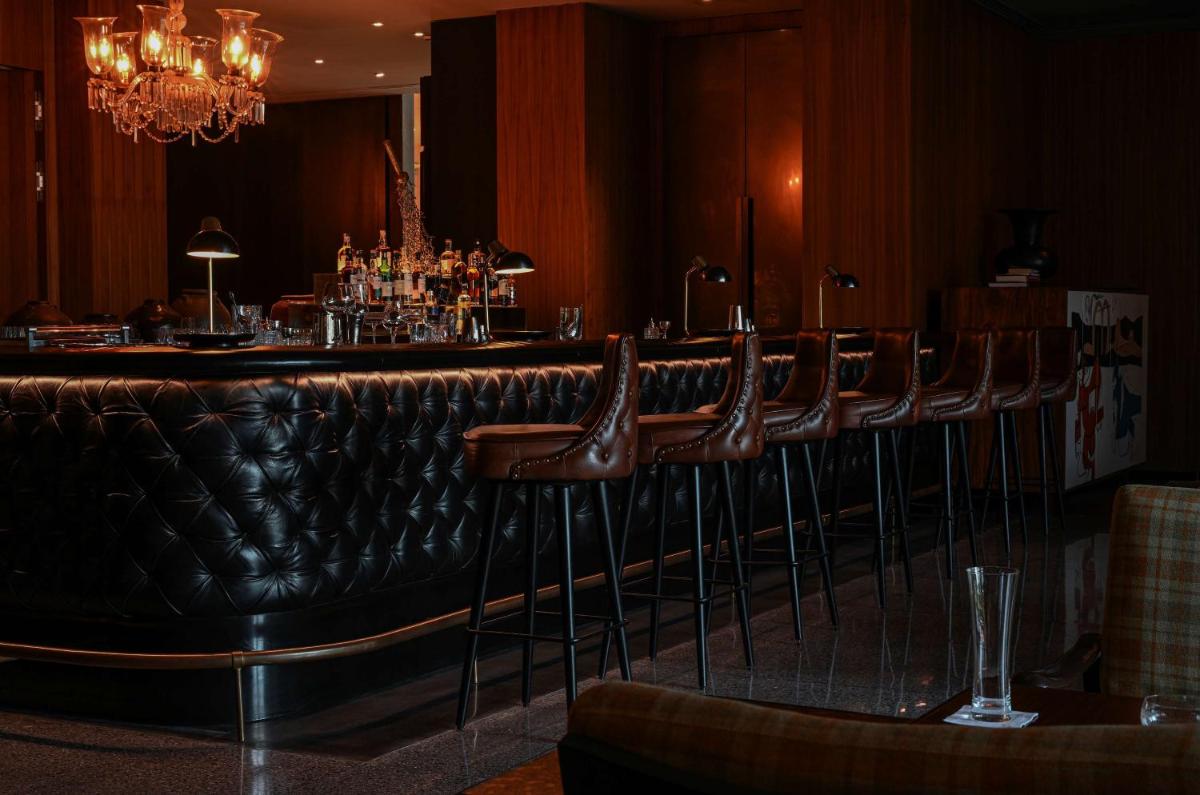 a bar with a row of brown leather stools at Grand Hyatt Gurgaon in Gurgaon