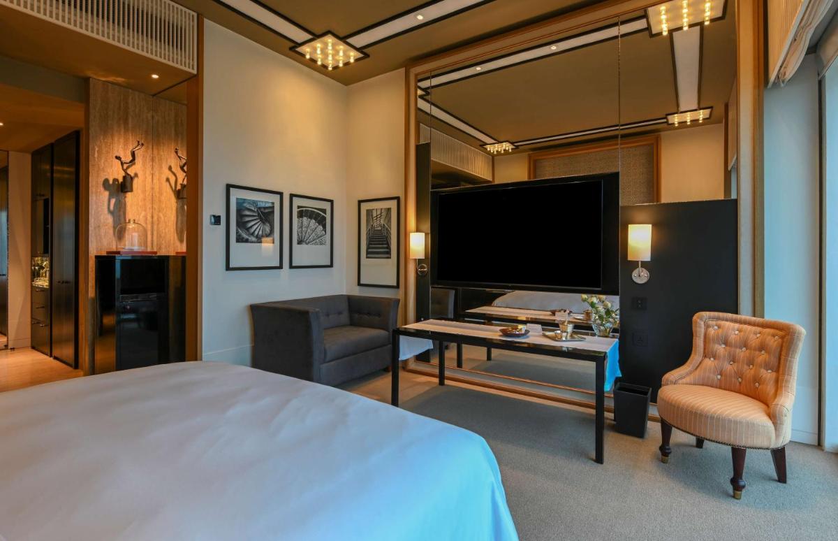 a bedroom with a bed and a desk and a tv at Grand Hyatt Gurgaon in Gurgaon