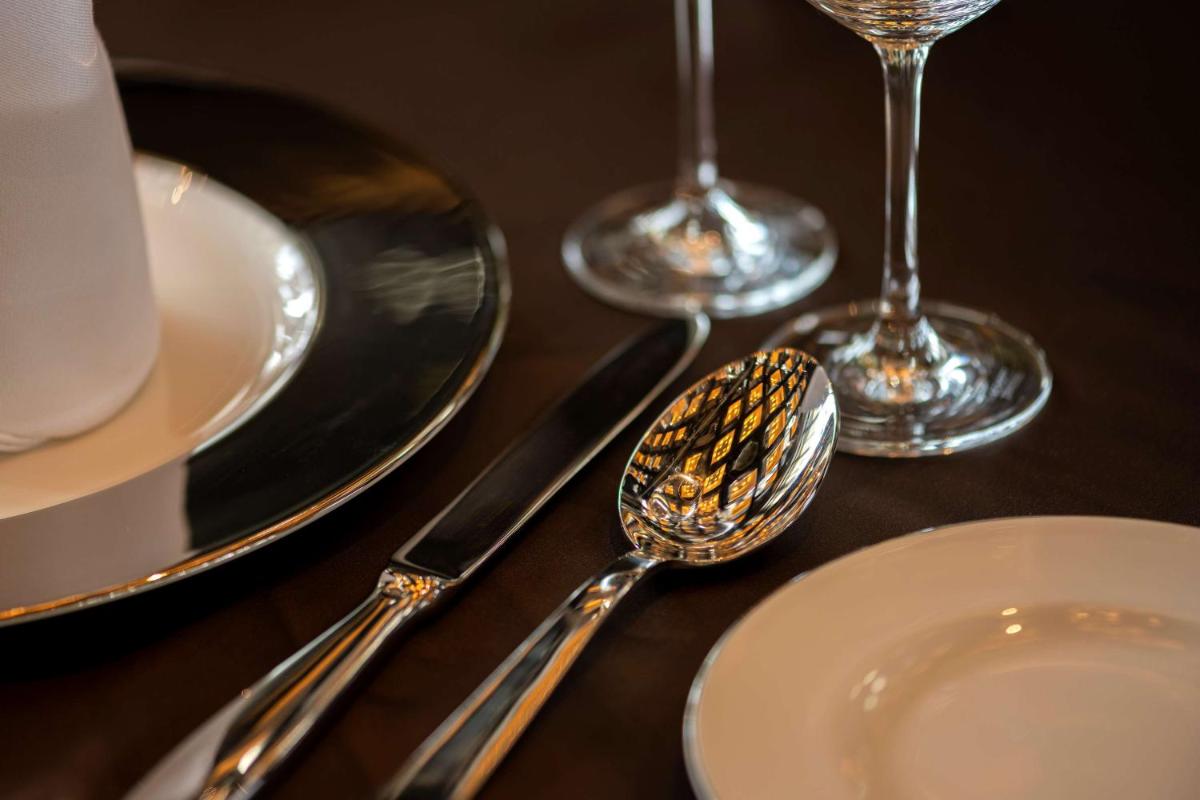 a table with plates and spoons and wine glasses at Grand Hyatt Gurgaon in Gurgaon