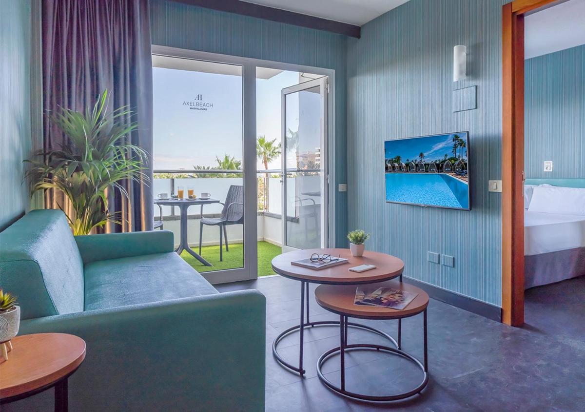 Habitación de hotel con sofá, mesas y cama en Axel Beach Maspalomas - Adults Only, en Playa del Inglés