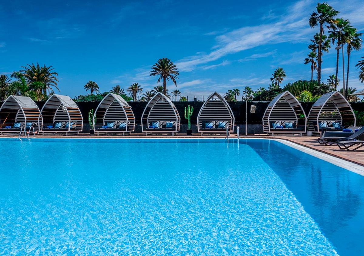 una gran piscina con edificios abovedados y palmeras en Axel Beach Maspalomas - Adults Only, en Playa del Inglés